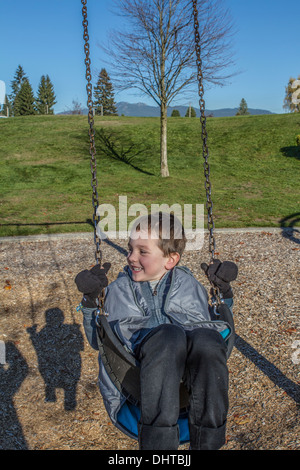 Model freigegeben, niedlich, Lächeln, lachen, 5 Jahre alter Junge, Spaß in der Natur auf der Schaukel. Stockfoto