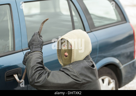 Räuber mit einem Brecheisen in der Nähe von der Autotür Stockfoto