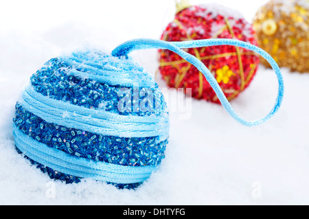 einige Weihnachtskugeln in verschiedenen Farben auf dem Schnee Stockfoto