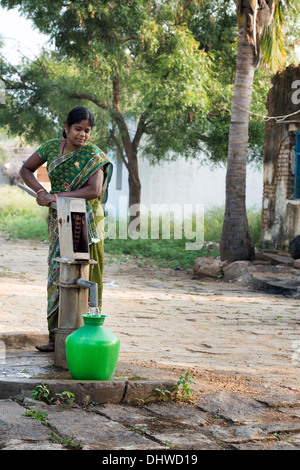 Indische Frau Füllung Kunststoff Wassertopf aus einem ländlichen Dorf Handpumpe. Andhra Pradesh, Indien Stockfoto