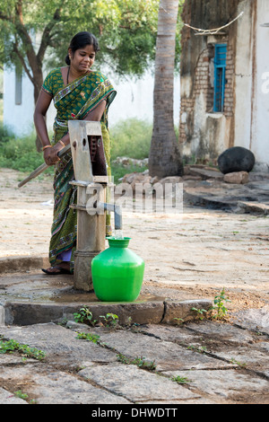 Indische Frau Füllung Kunststoff Wassertopf aus einem ländlichen Dorf Handpumpe. Andhra Pradesh, Indien Stockfoto