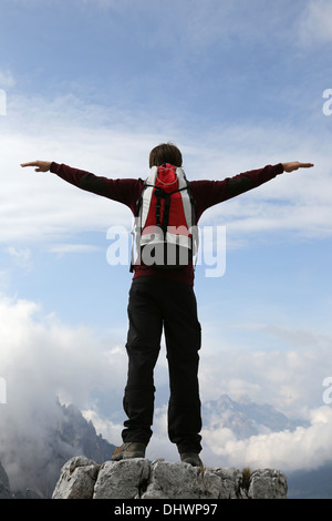 Ein junger Kletterer auf einem Berggipfel, streckte die Arme wie fliegen Stockfoto