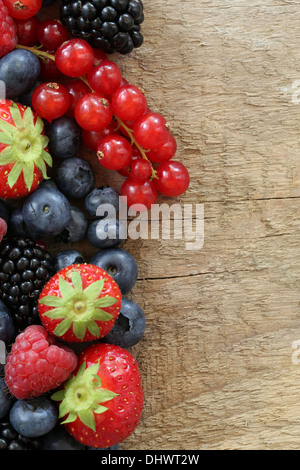 Fresh berries like strawberries, blueberries, red currants, raspberries and blackberries on a wooden board Stockfoto
