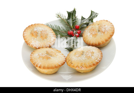 Mince Pies auf einem Teller mit einer Dekoration von Holly und Tannennadeln isoliert gegen weiß Stockfoto