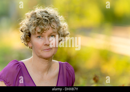 Frau applying lockiges Haar während des Sonnenuntergangs Stockfoto