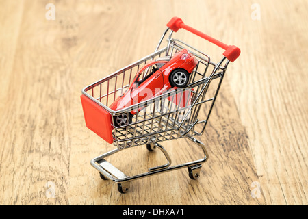 Ein Konzeptbild von einem teuren Sportwagen in einen Supermarkt Einkaufswagen Stockfoto