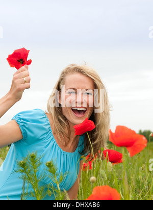 hübsche junge blonde Frau, Mohnblumen pflücken Stockfoto