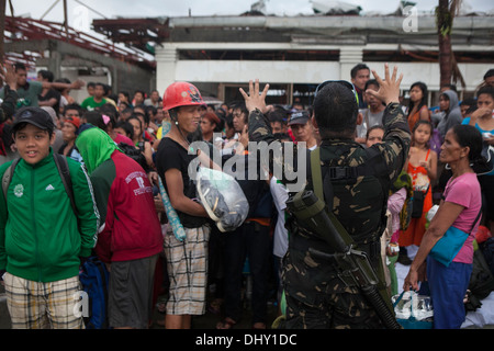 LEYTE, Republik der Philippinen – eine bewaffnete Kräfte der Philippinen Soldat gibt Anweisungen zu einer Masse auf Tacloban Air Base 14 November im Rahmen der Operation Damayan. Die Regierung der Philippinen ist eng mit internationalen Hilfsaktionen e Koordination Stockfoto