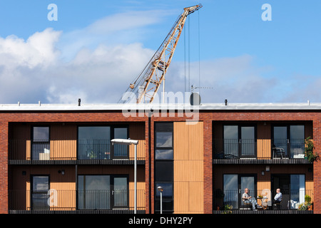 Zwei Männer auf einem Balkon in der neuen Häuser bauen auf Govan Road, Glasgow Sitzen mit dem luffing Kran von Fairfield Werft Stockfoto