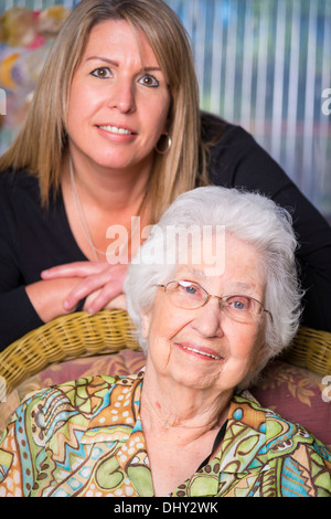 Porträt von ältere Frau in den 90er Jahren mit ihrer Reifen Enkelin in den 40er Jahren. Beide Lächeln beim Blick in die Kamera. Stockfoto