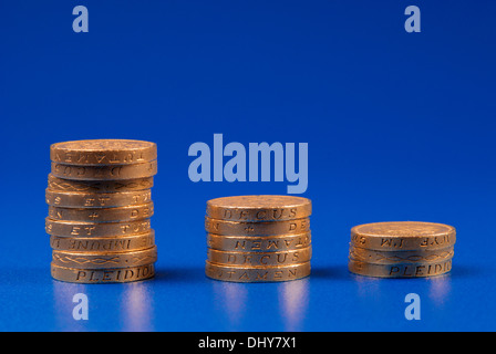Absteigenden Stapel von Münzen auf blauem Hintergrund Stockfoto