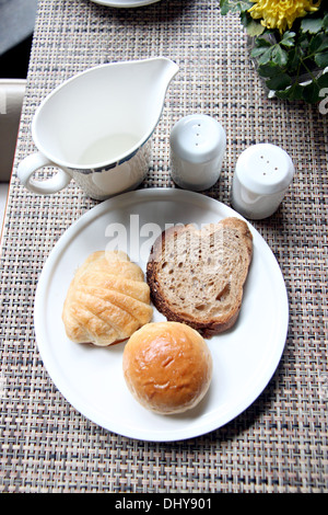 Höhe anzeigen Brot in einem weißen Teller und in der Nähe von Tasse Milch für das Frühstück. Stockfoto