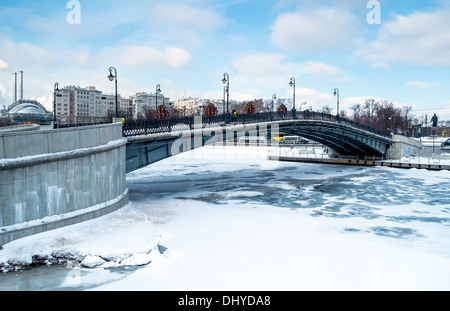 Blick auf eine der vielen Brücken über dem Fluss Moskwa in Moskau, während der Winterzeit mit einem zugefrorenen Fluss. Stockfoto