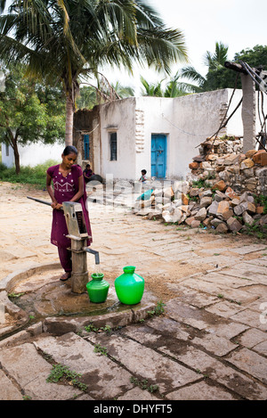 Indische Teenager-Mädchen Pumpen von Wasser aus einer Hand-Pumpe in einen Topf in einem indischen Dorf. Andhra Pradesh, Indien. Stockfoto