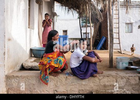 Indische Mutter Flechten Haar Töchter für die Schule in einem indischen Dorf. Andhra Pradesh, Indien Stockfoto