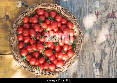 Cherry-Tomaten in Korb auf Holztisch Stockfoto