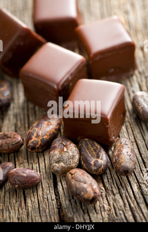 Pralinen mit Kakaobohnen auf hölzernen Hintergrund Stockfoto