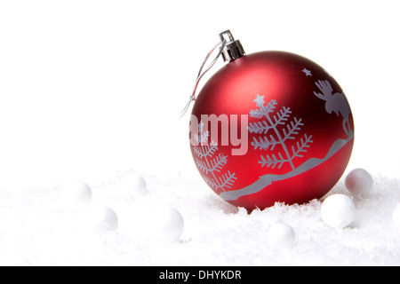 Rote Christbaumkugel mit Weihnachtsbaum auf Schnee Stockfoto