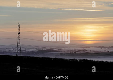 Kilbirnie, North Ayrshire, Schottland, Großbritannien, Sonntag, 17. November 2013. Sonnenaufgang über einem Strommast in einem nebligen Garnock Valley Stockfoto