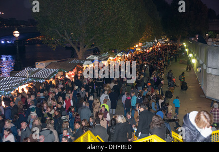 Massen gehen in der Nacht entlang der South Bank in London mit seinen bunten Ständen, UK Stockfoto