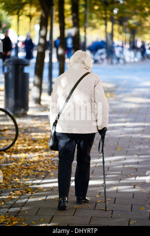 Alte Dame gehen mit Stock Stockfoto