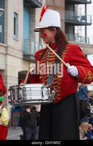 Poole, Großbritannien Sonntag, 17. November 2013. Der Weihnachtsmann, Santa Claus, kommt in Poole. Er kam auf ein Rettungsboot mit rnli Crew, bereit für die Santa Parade mit Massen saeumten die Strassen, um ihn zu begrüßen. Drummer auf Stelzen. Frau Person auf Stelzen stehend als Schlagzeuger gekleidet. Credit: Carolyn Jenkins/Alamy leben Nachrichten Stockfoto