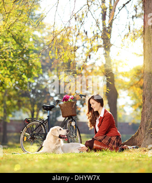 Hübsche Frauen sitzen mit ihrem Labrador Retriever Hund in einem park Stockfoto