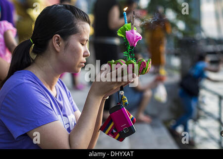 Bangkok, Thailand. 17. November 2013. Eine Frau betet vor schwebt ihr Krathong in den Chao Phraya River in der Nähe von Wat Yannawa in Bangkok. Loy Krathong (auch geschrieben als Loi Krathong) wird jährlich in ganz Thailand und bestimmte Teile von Laos und Burma (im Shan-Staat) gefeiert. Der Name könnte übersetzt '' schwebende Krone '' oder '' schwimmende Dekoration '' und stammt aus der Tradition in der Herstellung von heiter Dekorationen, die dann auf einem Fluss geschwommen sind. Stockfoto