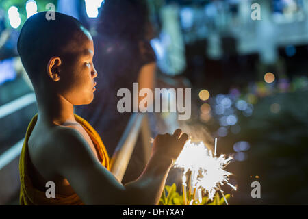 Bangkok, Thailand. 17. November 2013. Ein buddhistische Anfänger leuchtet Wunderkerzen auf einem Krathong war er in den Chao Phraya River in der Nähe von Wat Yannawa schweben. Loy Krathong (auch geschrieben als Loi Krathong) wird jährlich in ganz Thailand und bestimmte Teile von Laos und Burma (im Shan-Staat) gefeiert. Der Name könnte übersetzt '' schwebende Krone '' oder '' schwimmende Dekoration '' und stammt aus der Tradition in der Herstellung von heiter Dekorationen, die dann auf einem Fluss geschwommen sind. Stockfoto