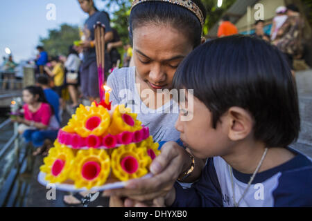 Bangkok, Thailand. 17. November 2013. Eine Mutter und ihr Sohn beten, bevor ihre Krathong im Chao Phraya River an Wat Yannawa auf Loy Krathong in Bangkok treiben. Loy Krathong (auch geschrieben als Loi Krathong) wird jährlich in ganz Thailand und bestimmte Teile von Laos und Burma (im Shan-Staat) gefeiert. Der Name könnte übersetzt '' schwebende Krone '' oder '' schwimmende Dekoration '' und stammt aus der Tradition in der Herstellung von heiter Dekorationen, die dann auf einem Fluss geschwommen sind. Stockfoto