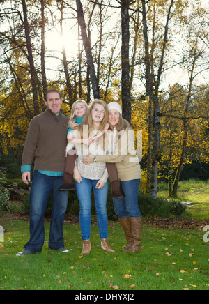 Vertikale Foto Familie stand vor Bäumen, mit Sonnenlicht durch, während ein schöner Tag im Herbst-Saison Stockfoto