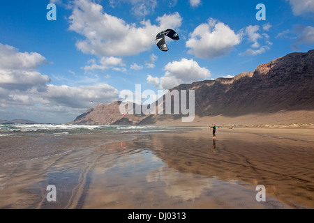 Mann-Kitesurfen auf windigen Famara Strand Risco de Famara im Hintergrund Stockfoto