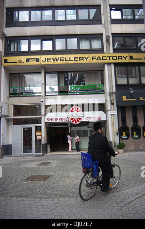 Ein Mann in orthodoxen jüdischen Bekleidung Fahrräder durch ein Quadrat in der Nähe eines Einkaufszentrums im Diamantenviertel von Antwerpen Stockfoto