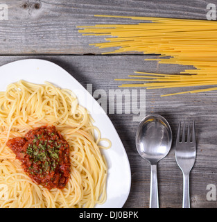 Spaghetti Bolognese mit Rindfleisch-Tomatensauce und rohen Nudeln auf hölzernen Hintergrund Stockfoto