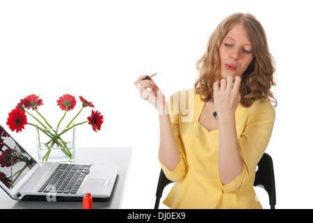 blonde Frau roten Nagellack auf die Nägel zu bringen und bläst zum Trocknen Stockfoto