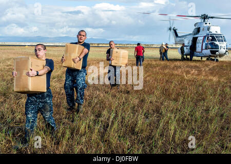 US Navy Matrosen entladen Hilfsgüter, die an Land, von einem SA-330J Puma-Hubschrauber in der Nachmahd des Super Taifun Haiyan 17. November 2013 in Tacloban, Philippinen per Luftbrücke transportiert wurden. Stockfoto