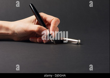 Hand mit Stift auf schwarzem Hintergrund Stockfoto