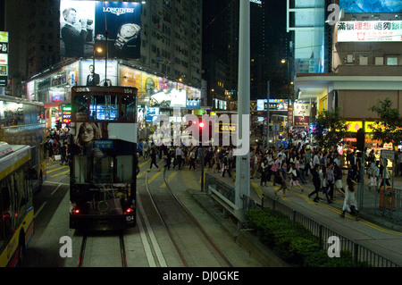 Straßenbahnen und Busse warten an der Ampel wird Käufern und Touristen überqueren Sie die Straße in Hong Kong bei Nacht Stockfoto