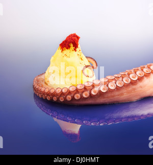 Octopus Tentacle gleiten über eine Kartoffel auf einem blauen Gradienten Hintergrund. Stockfoto