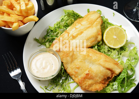 Ein Teller mit gebratenen Fisch und Chips auf Salat serviert Stockfoto
