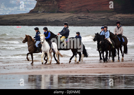 Gruppe von Pferden und Reitern am Strand von Paignton, Torbay, Devon, England, Vereinigtes Königreich Stockfoto