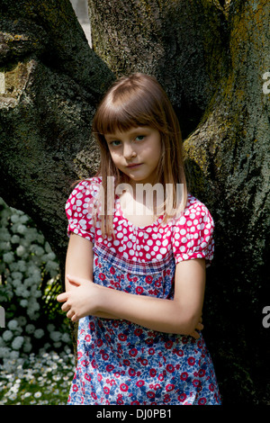 kleines Mädchen an einen Baum gelehnt Stockfoto