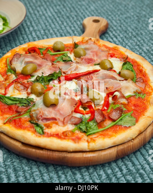 zubereitete Pizza mit Spinat, Oliven, Schinken Stockfoto