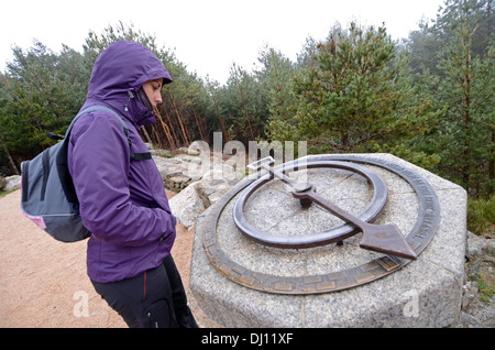 Junge Frau, die bei Compass auf einem Felsen beim Wandern in Scheidegebirges, höchsten Berggipfel in der Mountain Range Guadarrama Stockfoto