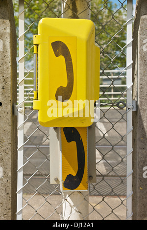 Gelbe Bahn Telefonzelle gegen Wire mesh Art Maschendrahtzaun. Stockfoto