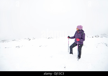 Junge Frau Wandern im verschneiten Tag im Peñalara, höchsten Berggipfel in der Bergkette der Sierra de Guadarrama, Spanien Stockfoto