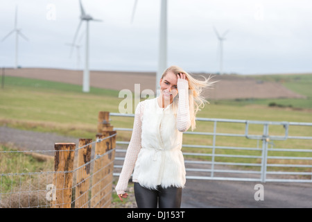 Interessante blonde behaarte Frau auf dem Lande mit einer Windfarm im Hintergrund Stockfoto
