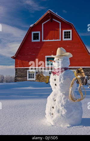 Schneemann verkleidet als Cowboy steht man vor einem Vintage rote Scheune im Winter; Palmer Alaska Usa Stockfoto