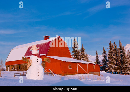 Schneemann verkleidet als Cowboy steht man vor einem Vintage rote Scheune im Winter; Palmer Alaska Usa Stockfoto