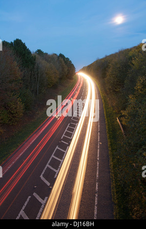 Transport auf der Straße. Schlierenbildung Autolichter vom Berufsverkehr fahren runden Abend der Dorchester umgehen, mit dem Vollmond steigt. Dorset, England, Vereinigtes Königreich Stockfoto